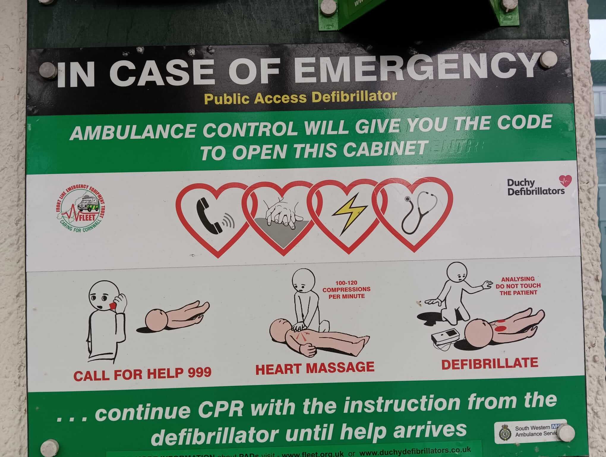 Signage connected with a second AED with symbols and instructions about calling 999, performing CPR and delivering a shock. It reads: In case of emergency, public access defibrillator.. Ambulance Control will give you the code to open this cabinet.